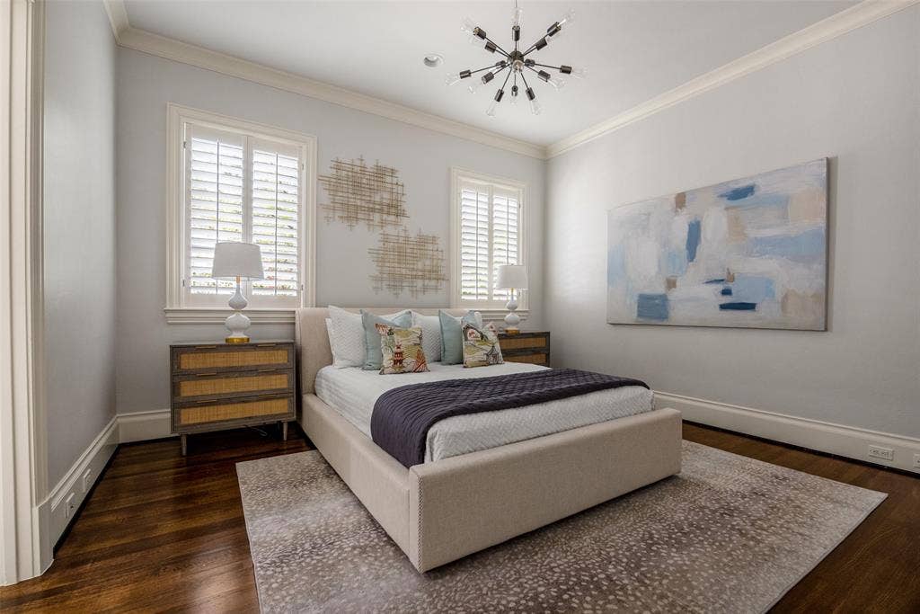 Room featuring wood-finish flooring, crown molding, and two windows fitted with white plantation shutters