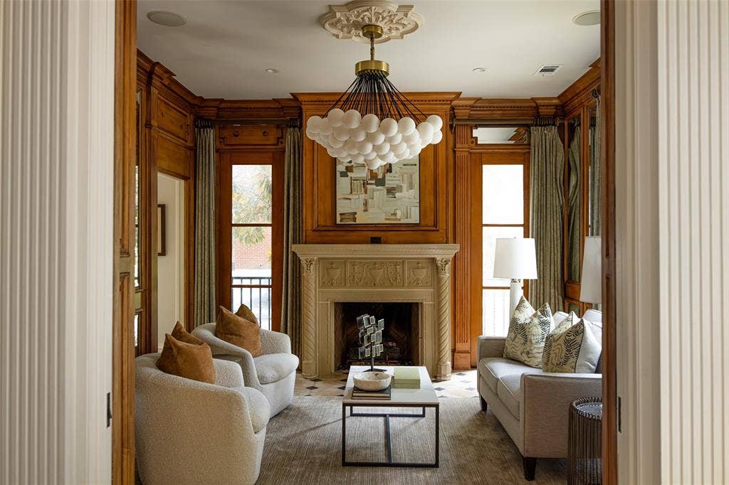 Hardwood paneled walls featuring intricate millwork, a carved stone fireplace, and a decorative ceiling medallion