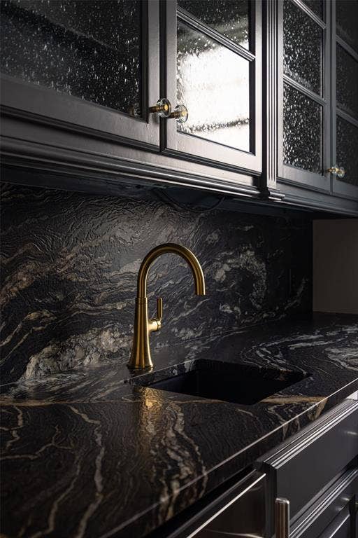 Striking black and gold veined countertop featuring a gold-toned faucet and integrated sink