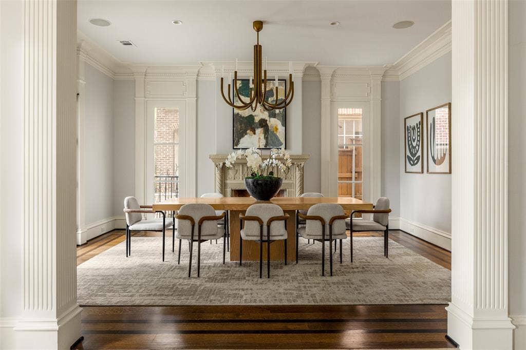Formal dining room featuring hardwood flooring, extensive crown molding, a decorative fireplace, and transom windows