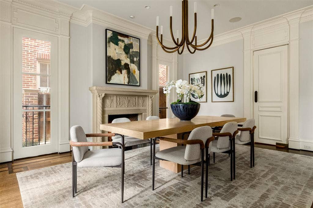 Formal dining area featuring rich wood-finish flooring, an ornate fireplace with a carved stone mantel, and a multi-arm chandelier