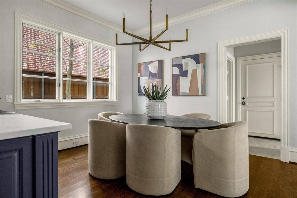 Dining area featuring wood-finish flooring, a contemporary linear chandelier, triple casement windows, and detailed crown molding