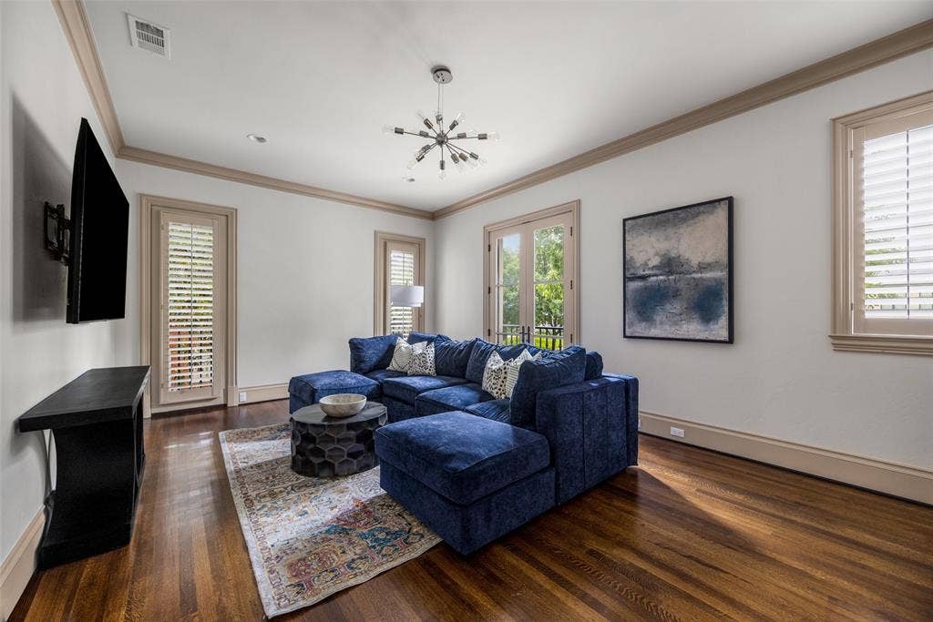Interior room with rich wood-finish flooring, light wall paint, and substantial crown molding