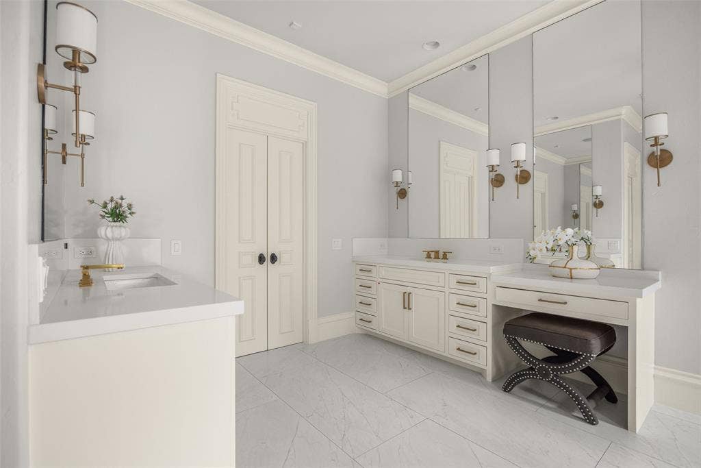 Bathroom featuring dual vanity areas with white countertops, integrated sinks, and gold-toned fixtures