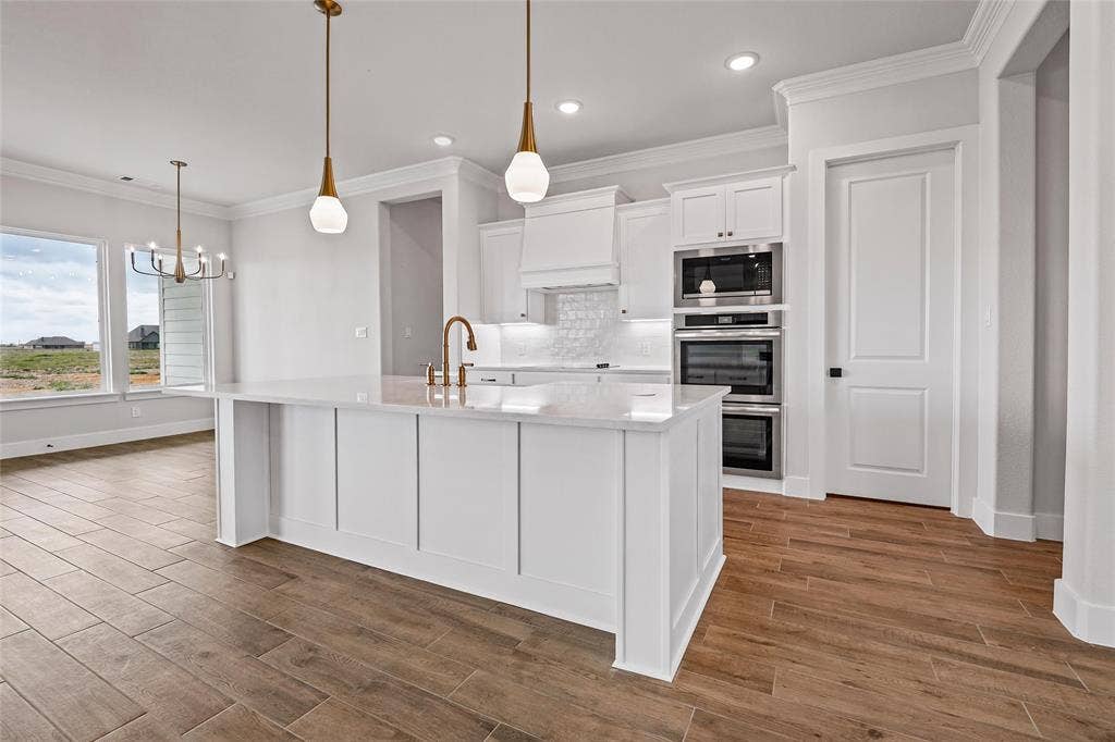 12413 Hornfels Drive, Krum, TX 76249 Gourmet kitchen featuring a large island with pendant lighting, stainless steel double ovens, and wood-finish flooring