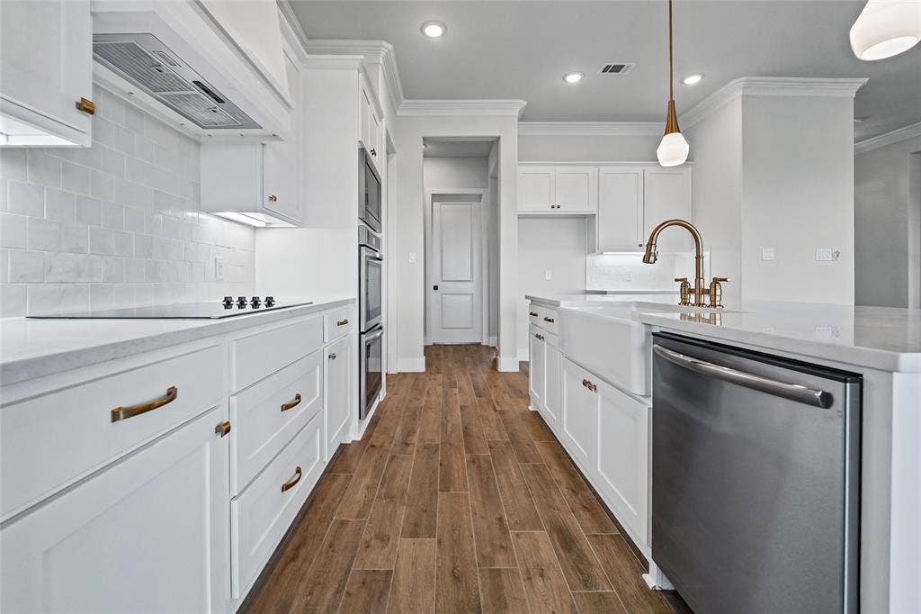 12413 Hornfels Drive, Krum, TX 76249 Gourmet kitchen featuring wood-finish flooring, white cabinetry with bronze hardware, stainless steel appliances, a farmhouse sink, and white subway tile backsplash