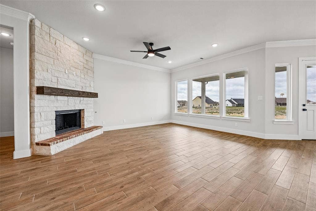 12413 Hornfels Drive, Krum, TX 76249 Spacious room featuring wood-finish tile flooring, a stone fireplace with a substantial wood mantel, a ceiling fan, and recessed lighting