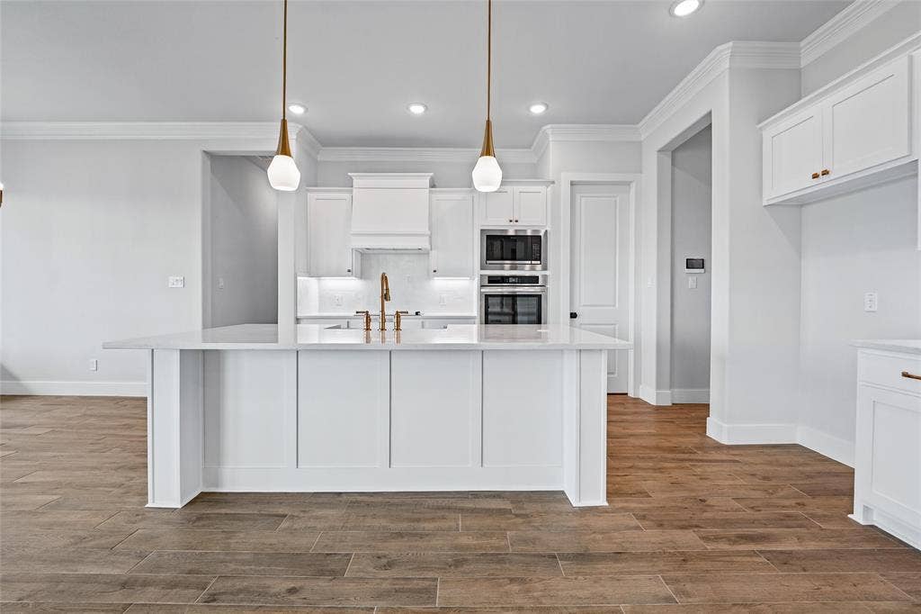 12413 Hornfels Drive, Krum, TX 76249 Kitchen island with a light-toned countertop, pendant lighting, stainless steel double ovens, a range hood, and wood-finish flooring