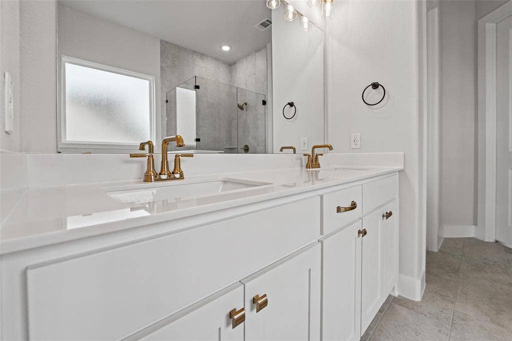 12413 Hornfels Drive, Krum, TX 76249 Dual vanity with white cabinetry, gold-tone hardware, and integrated rectangular sinks