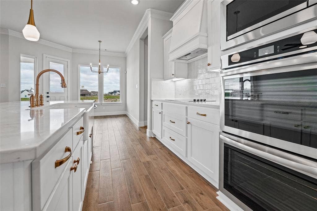 12413 Hornfels Drive, Krum, TX 76249 Kitchen featuring white cabinetry, built-in stainless steel appliances, wood-finish flooring, and light countertops with an integrated sink