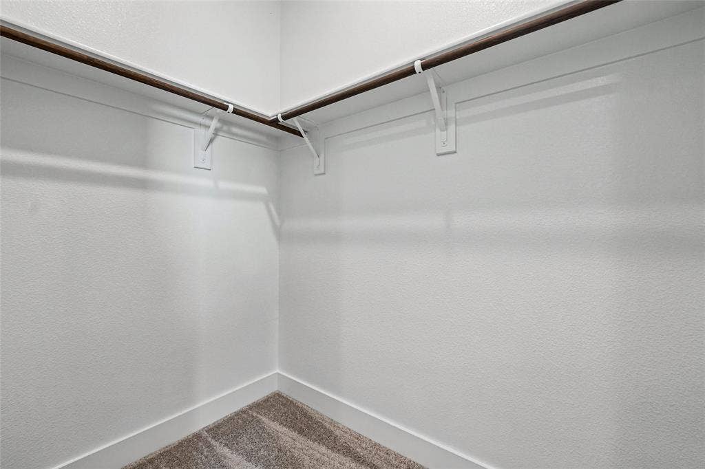 12413 Hornfels Drive, Krum, TX 76249 Carpeted closet with a wood-finish hanging rod and white wall brackets