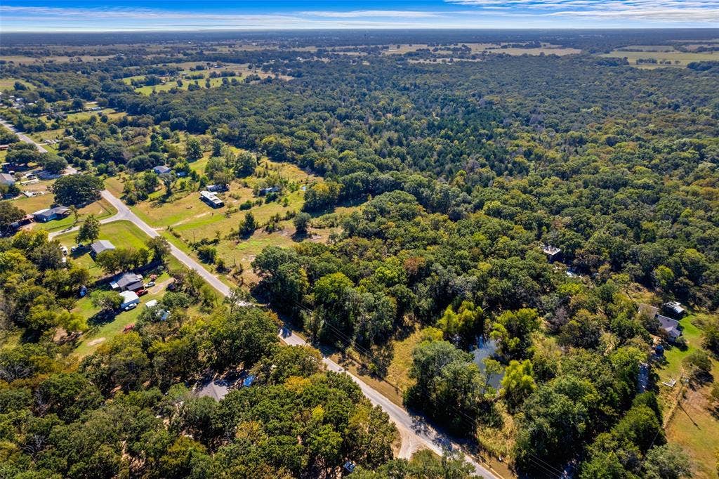 11691 Betty Lane, Kaufman, TX 75142 Expansive aerial view of a verdant landscape featuring extensive tree coverage, scattered residential properties, and a visible roadway