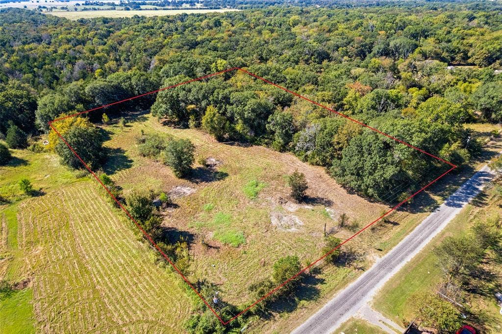 11691 Betty Lane, Kaufman, TX 75142 Expansive undeveloped land featuring a mix of open areas and mature trees, bordered by a paved road