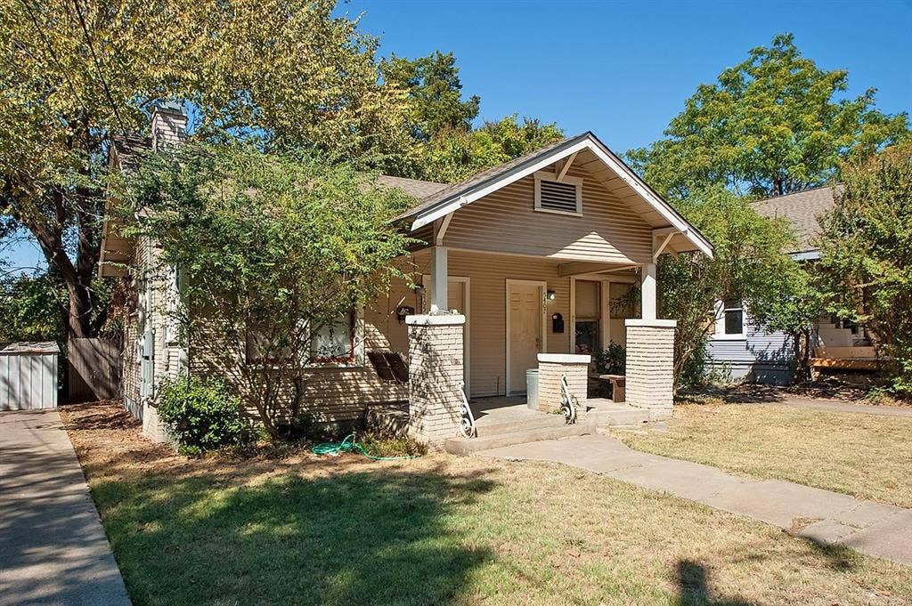 5405 Worth Street, Dallas, TX 75214 A cozy house with a charming front porch and a well-kept yard, creating a warm and inviting atmosphere.