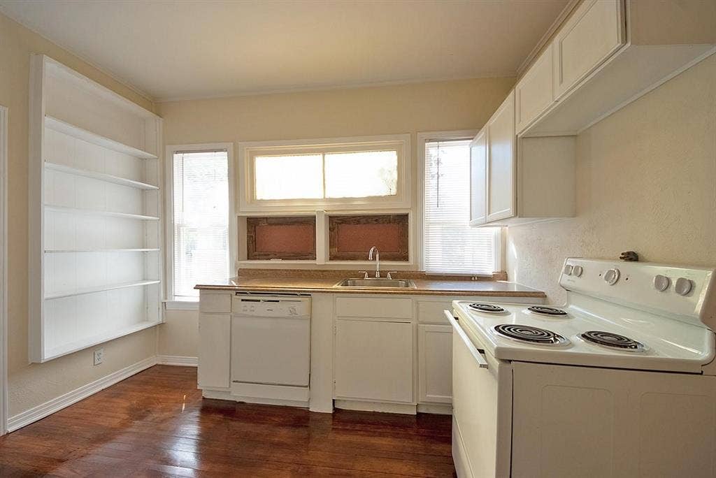 5405 Worth Street, Dallas, TX 75214 A cozy kitchen with white cabinets and shelves, dishwasher and a stove, creating a clean and inviting cooking space.