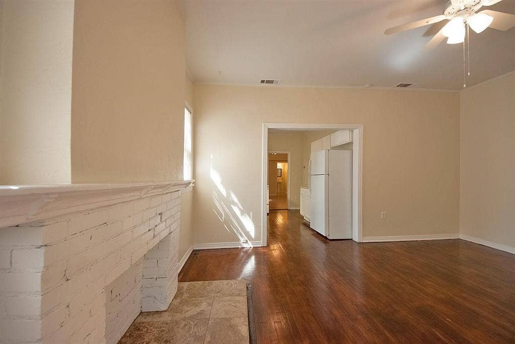 5405 Worth Street, Dallas, TX 75214 A spacious living room featuring hardwood floors, a fireplace and a ceiling fan, creating a bright and airy atmosphere.