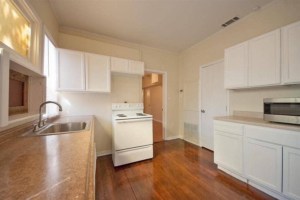 5405 Worth Street, Dallas, TX 75214 A cozy kitchen with white cabinets, a microwave and a stove, creating a clean and inviting cooking space.