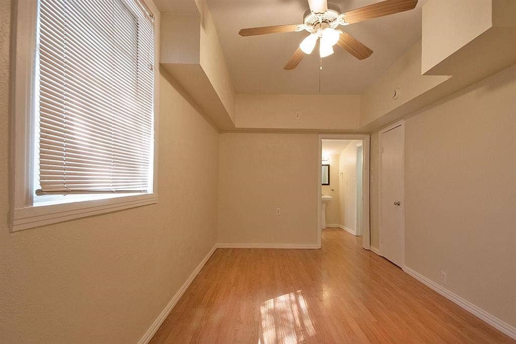 5405 Worth Street, Dallas, TX 75214 A cozy bedroom with a window featuring hardwood floors and a ceiling fan, perfect for keeping cool and comfortable.