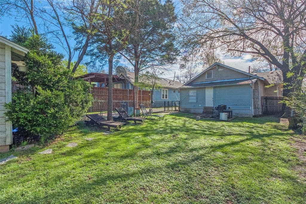 5405 Worth Street, Dallas, TX 75214 A spacious backyard with trees featuring a patio area and a grill, perfect for outdoor cooking and relaxation.
