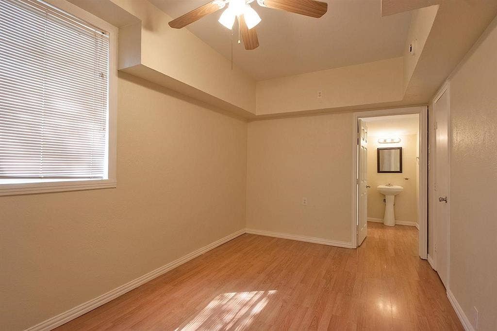 5405 Worth Street, Dallas, TX 75214 A cozy bedroom with a window featuring hardwood floors and a ceiling fan, perfect for keeping cool and comfortable.