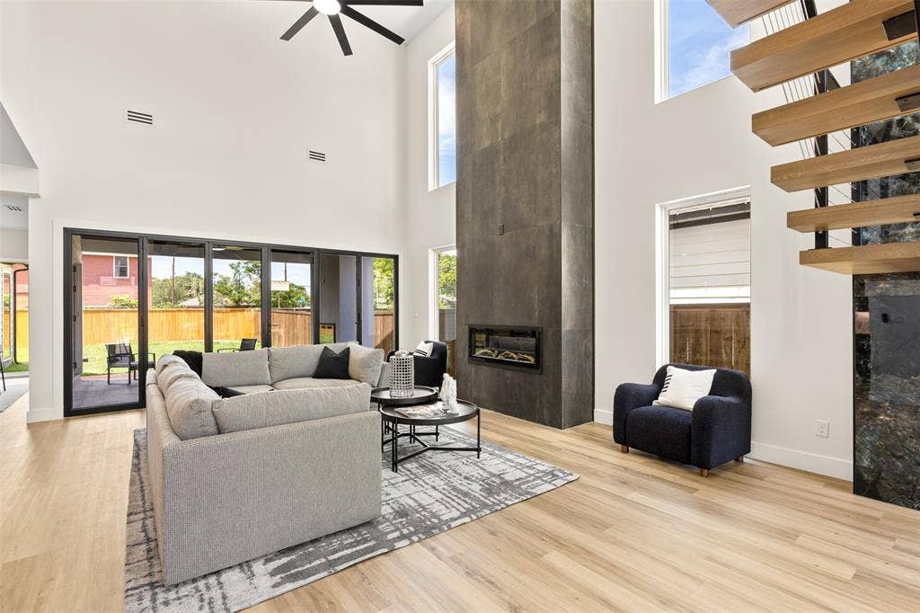 1407 Pueblo Street, Dallas, TX 75212 Vaulted living space featuring a floor-to-ceiling fireplace with an inset electric firebox, an open-tread staircase with wood risers, a ceiling fan, and wood-finish flooring