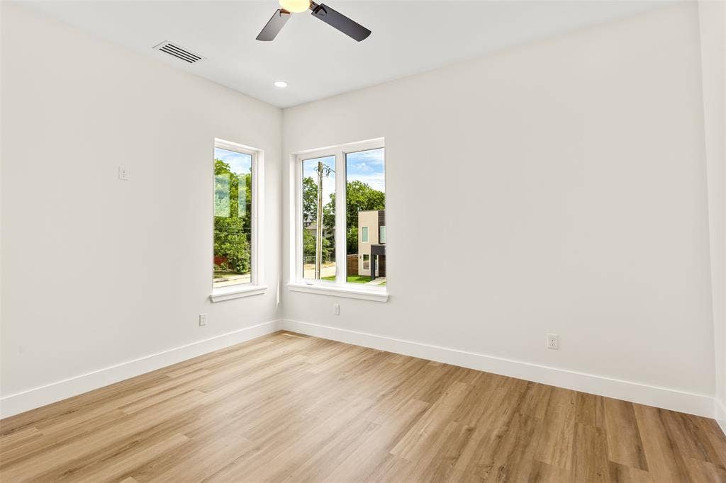 1407 Pueblo Street, Dallas, TX 75212 Light-filled room featuring wood-finish flooring, two large windows, a ceiling fan with integrated lighting, recessed ceiling lighting, and crisp white walls