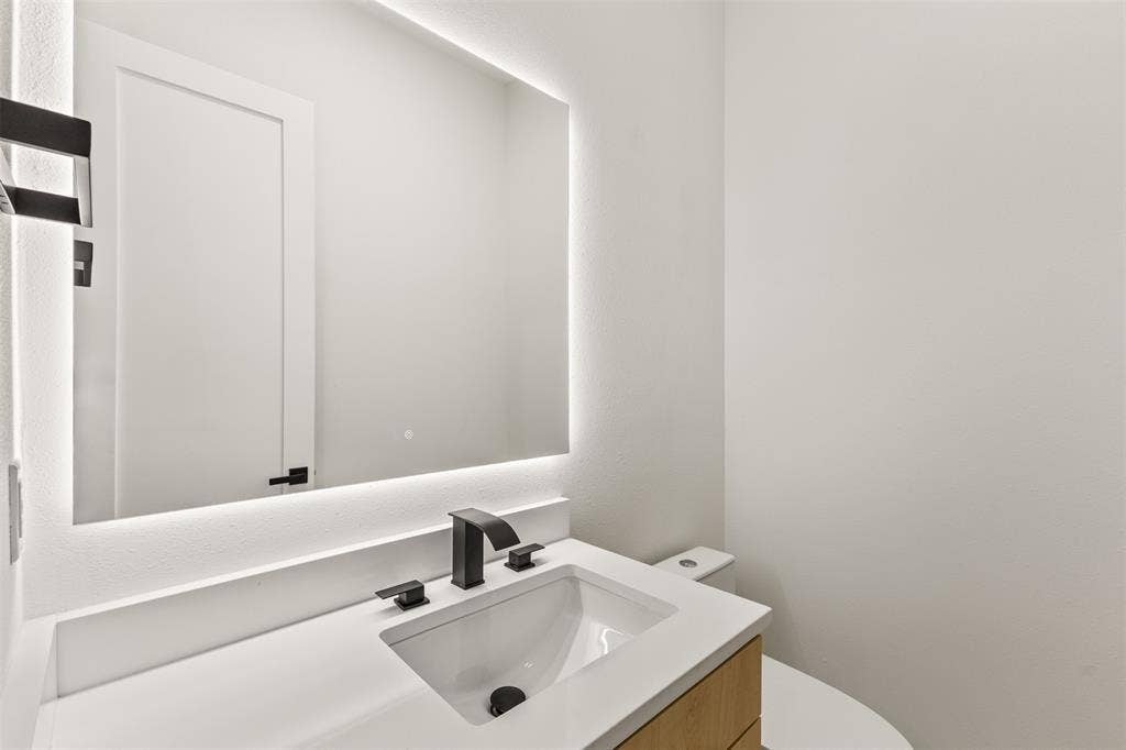 1407 Pueblo Street, Dallas, TX 75212 Contemporary vanity featuring a rectangular undermount sink, matte black faucet, and a light wood-finish cabinet
