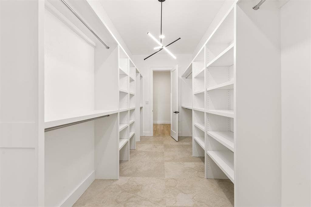 1407 Pueblo Street, Dallas, TX 75212 Spacious walk-in closet featuring extensive built-in shelving, hanging rods, recessed lighting, and large format tile flooring
