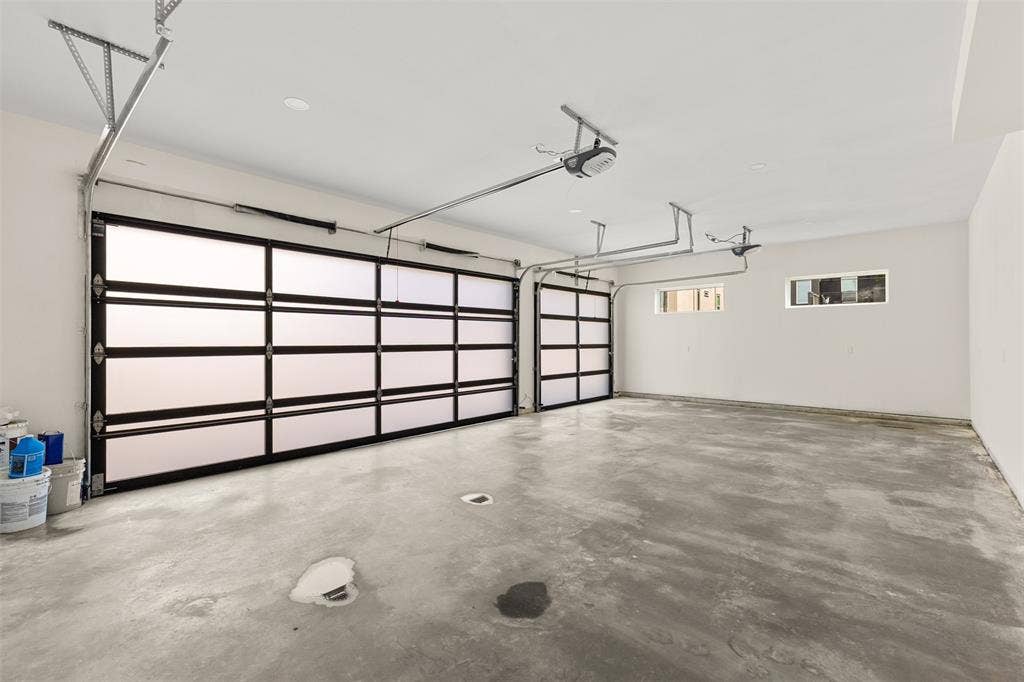1407 Pueblo Street, Dallas, TX 75212 Spacious garage featuring two modern glass panel doors, a concrete floor, and multiple transom windows providing natural light