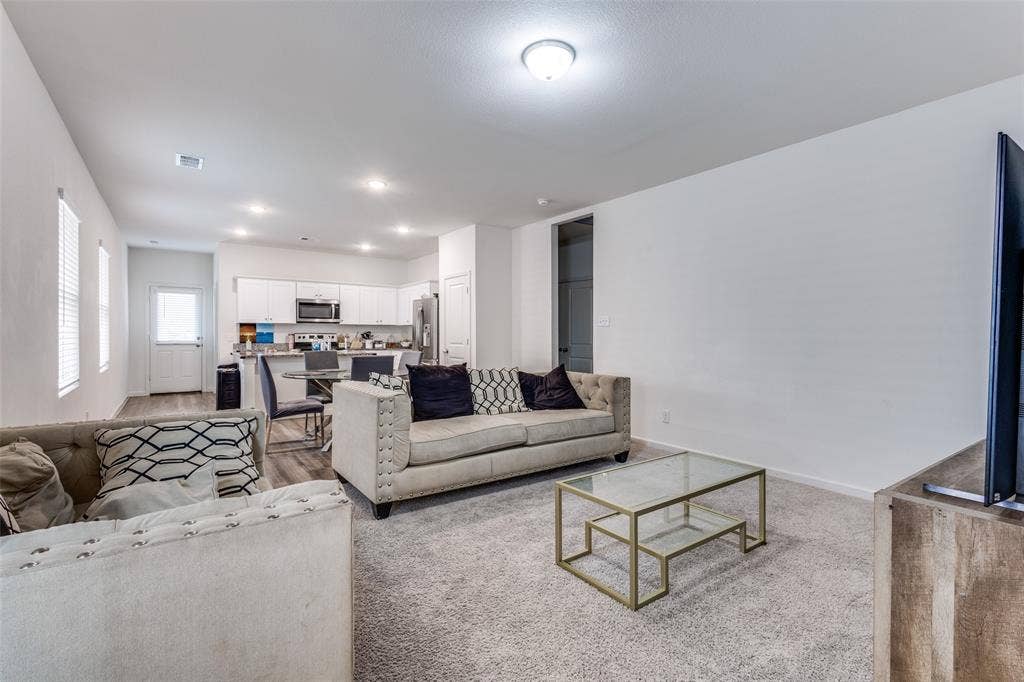 Open-concept living space featuring light carpeting and neutral wall tones