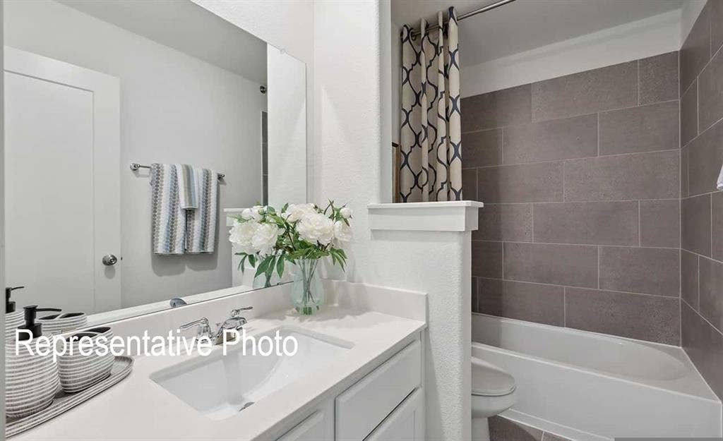 Bathroom featuring a white vanity with an integrated sink, polished chrome faucet, and quartz countertop