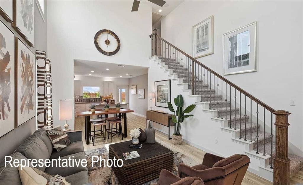 Two-story living area featuring a prominent staircase with iron balusters and wood handrails, high ceilings, recessed lighting, and wood-finish flooring