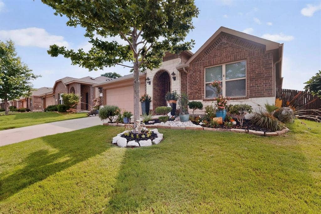 698 Langdon Street, Lavon, TX 75166 Brick and stone facade residence featuring an arched entryway, established landscaping, two-car garage, and a fenced backyard