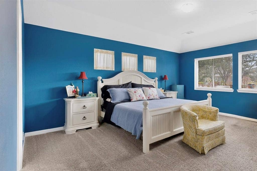 698 Langdon Street, Lavon, TX 75166 Bedroom featuring vaulted ceiling, two large windows, carpet flooring, and blue painted walls
