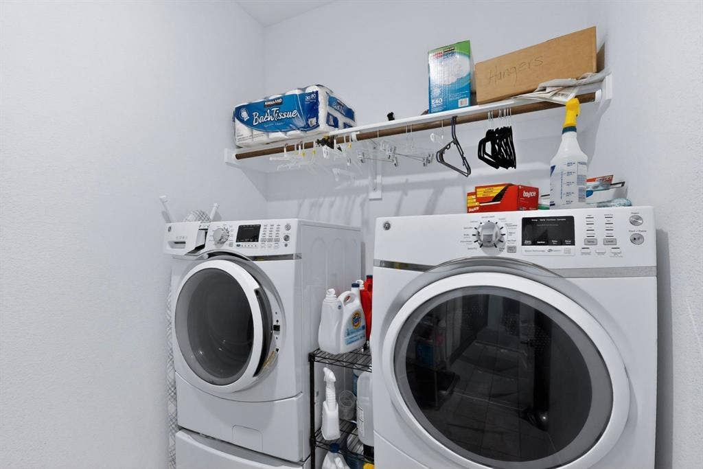 698 Langdon Street, Lavon, TX 75166 Dedicated laundry area featuring a white front-loading washer and dryer set, a high-mounted storage shelf, and a hanging rod for convenience