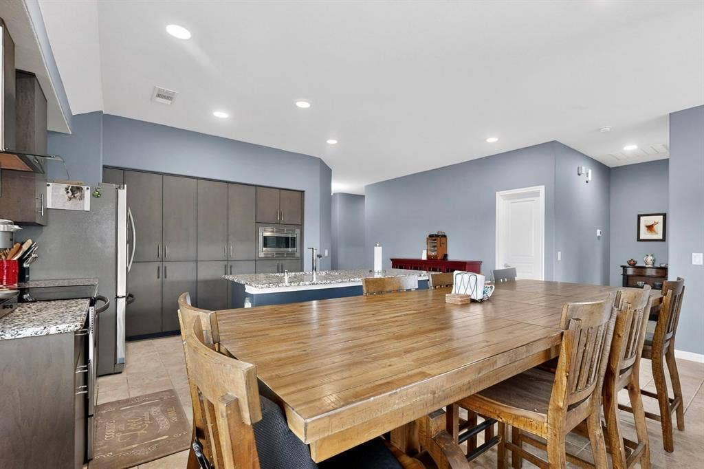 698 Langdon Street, Lavon, TX 75166 Open-concept kitchen and dining area featuring a spacious wood-finish dining table, recessed lighting, and tile flooring