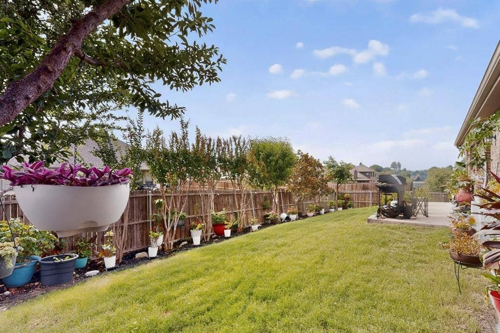 698 Langdon Street, Lavon, TX 75166 Expansive backyard featuring a lush lawn, concrete patio, and a privacy fence