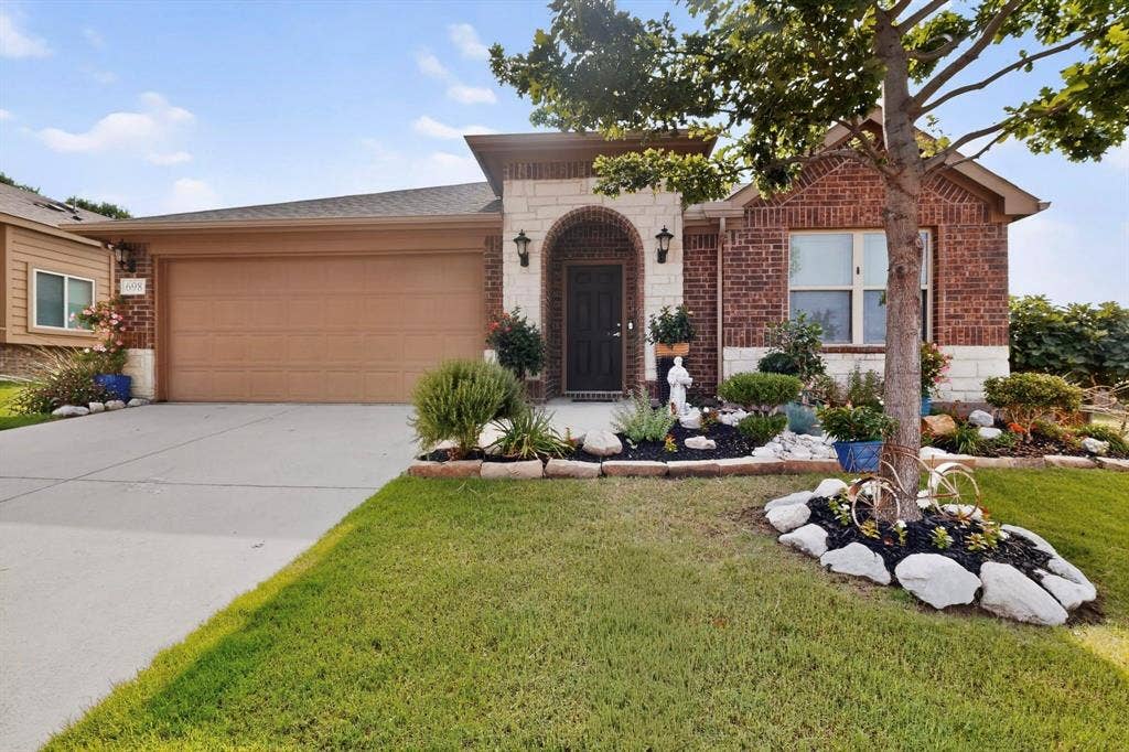 698 Langdon Street, Lavon, TX 75166 Brick and stone façade residence featuring an arched entry, a two-car garage, and established landscaping