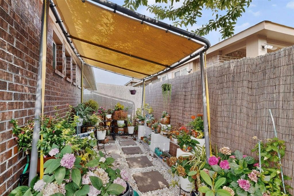 698 Langdon Street, Lavon, TX 75166 Covered side yard featuring a brick facade, privacy screening, stone step pathway, gravel ground cover, and overhead shade structure