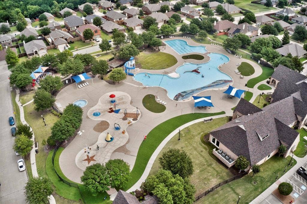 698 Langdon Street, Lavon, TX 75166 Community amenities featuring a large resort-style pool with a water slide, a separate splash pad, multiple shaded lounge areas, and surrounding green spaces