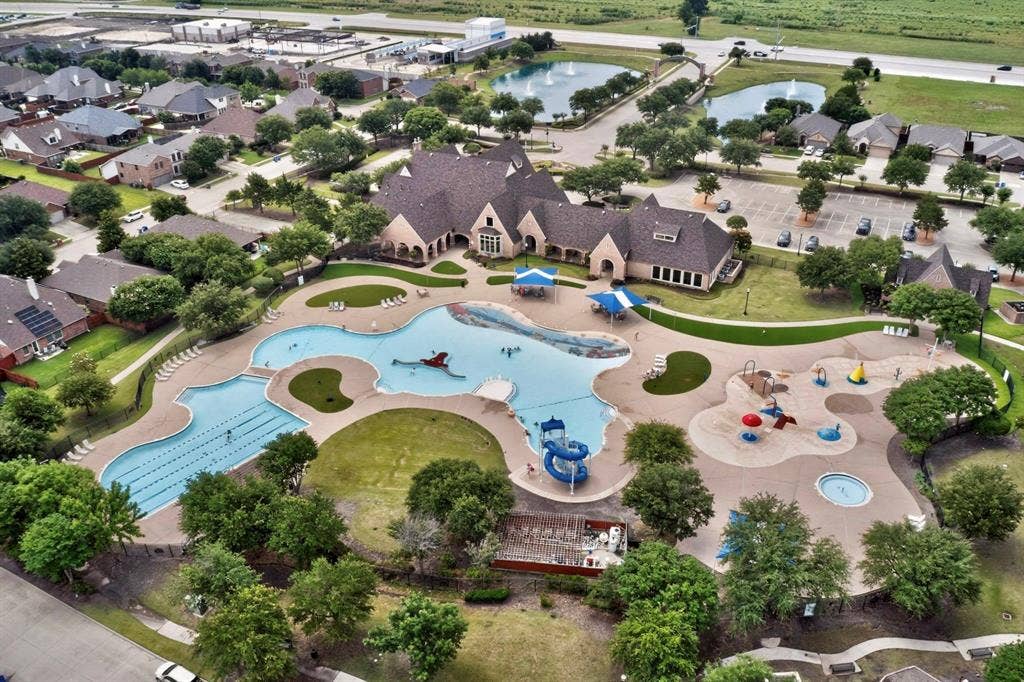 698 Langdon Street, Lavon, TX 75166 Expansive aquatic center featuring a multi-section swimming pool with lap lanes and a water slide, a separate splash pad area, and surrounding green spaces