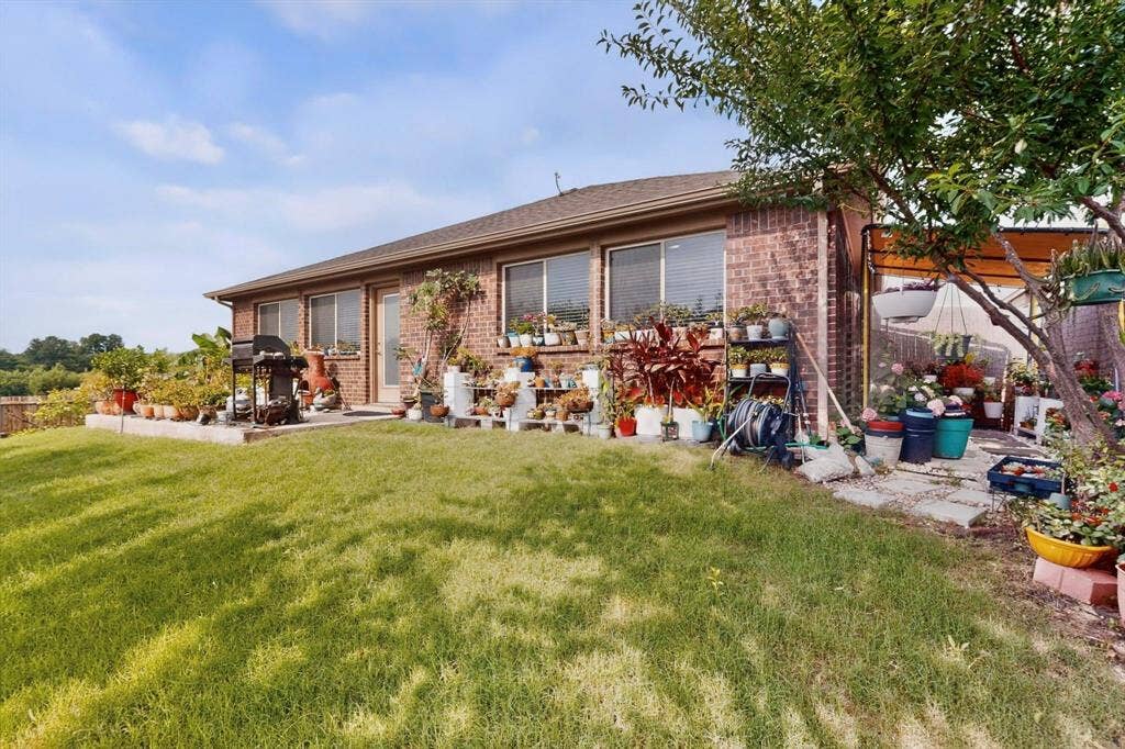 698 Langdon Street, Lavon, TX 75166 Brick exterior with multiple windows, a rear patio, and a manicured lawn
