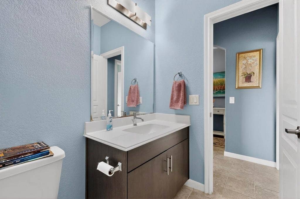 698 Langdon Street, Lavon, TX 75166 Bathroom vanity featuring a white countertop with integrated sink, dark wood-finish cabinetry, and brushed nickel hardware