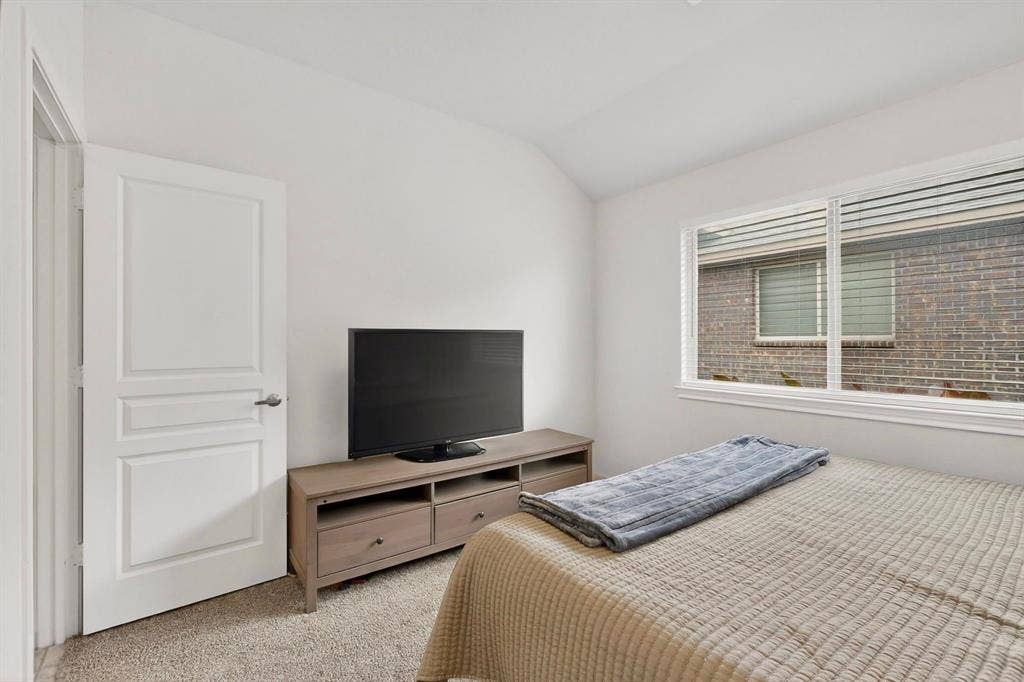 698 Langdon Street, Lavon, TX 75166 Carpeted room featuring a white interior door with panel detailing, a rectangular window with horizontal blinds, and a built-in media console with storage drawers