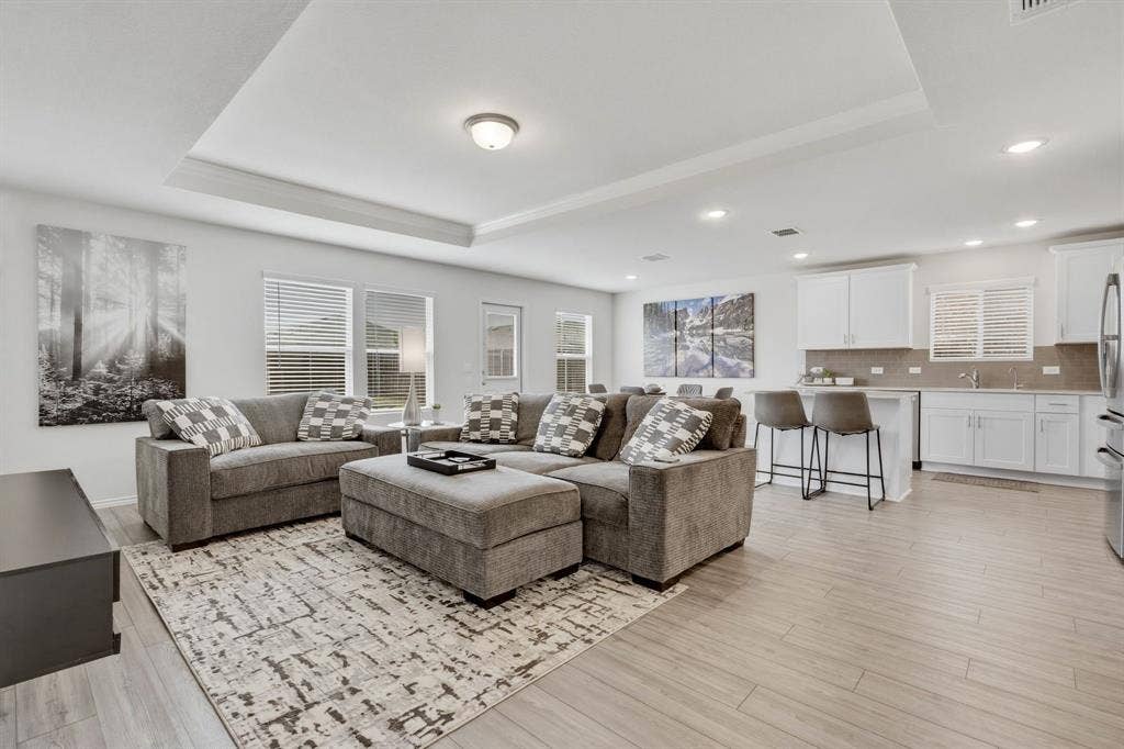 Open-concept living area featuring wood-look luxury vinyl plank flooring, a tray ceiling, and recessed lighting