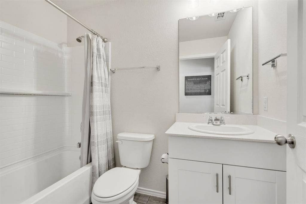 Bathroom featuring a white bathtub with subway tile surround, a single vanity with a white countertop and integrated sink, and a large wall mirror,