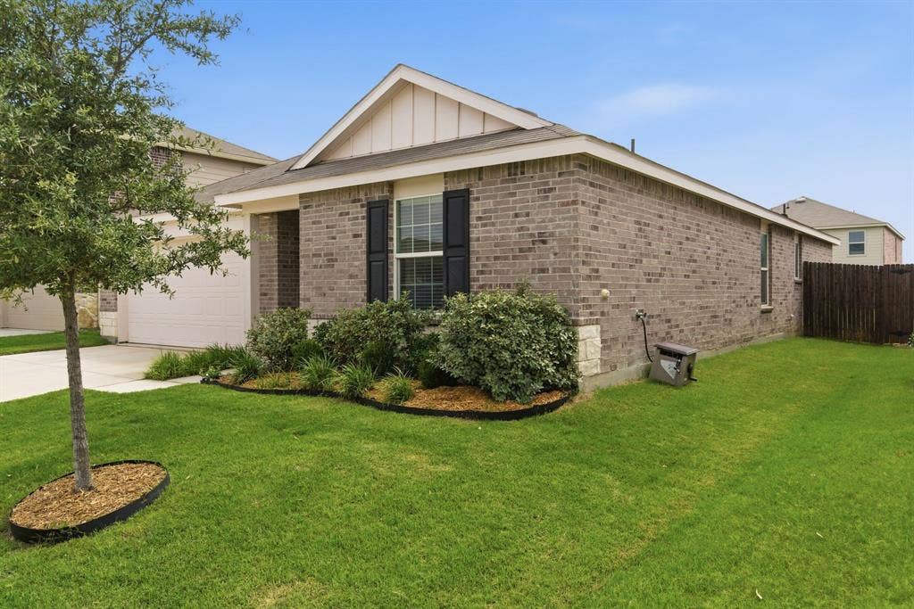 Brick exterior with a gabled roofline, decorative window shutters, and a two-car garage