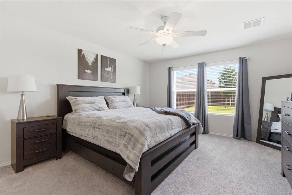 Bright room featuring plush carpeting and a white ceiling fan with integrated lighting