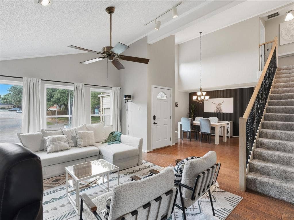 2812 Prescott Drive, Carrollton, TX 75006 Spacious living area with vaulted ceilings, wood-finish flooring, and ample natural light from multiple windows