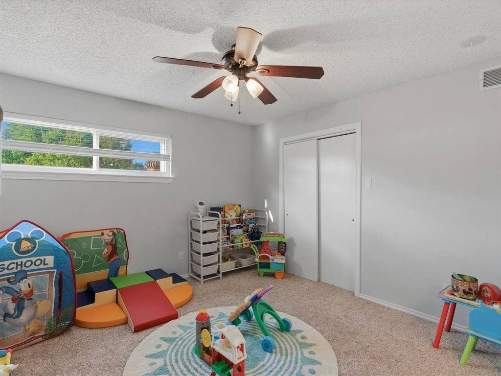2812 Prescott Drive, Carrollton, TX 75006 Carpeted room featuring a ceiling fan with light fixture, horizontal window, and sliding closet doors
